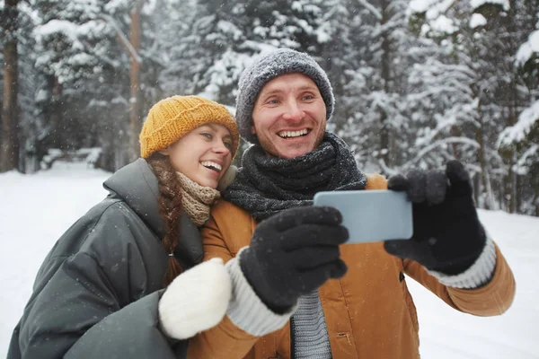 冬の森で時間を過ごしながらスマート フォンでリスを撮影 Winterwear の若いカップル — ストック写真