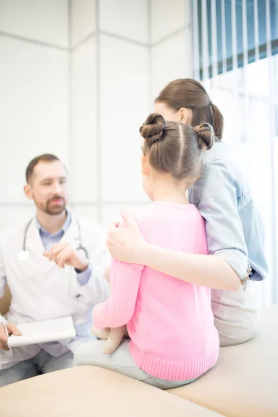 年轻女子在预约时抱女儿的后视及与医生在诊疗所交谈 — 图库照片