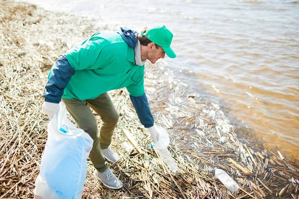 袋にごみを入れて水からペットボトルを取って生態組織の若いメンバー — ストック写真