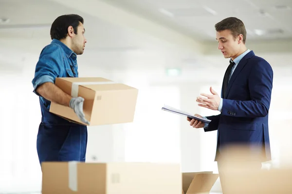 Confident businessman reading list of things that should have been delivered to new office and discussing it with worker of relocation service agency