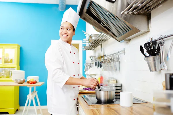 Jovem Chef Feliz Junto Fogão Misturando Alimentos Panela Enquanto Cozinha — Fotografia de Stock