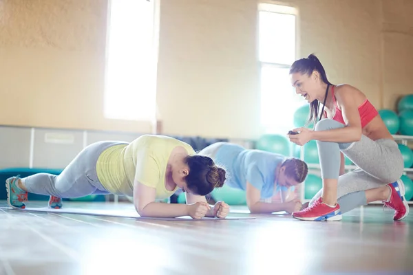 Fitnesstrainer Met Stopwatch Stimuleren Tot Formaat Vrouwen Doen Plank Sportschool — Stockfoto