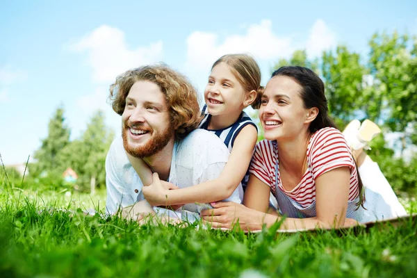在夏日的自然环境中 微笑的年轻人 他的妻子和女儿在绿色草地上休息的乐趣 — 图库照片