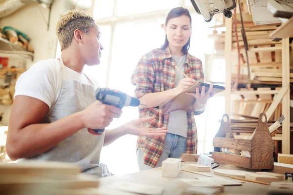 Młody Woodworker Wiertła Rozmawia Jej Kolega Dokonywanie Notatek Szkiców Notatniku — Zdjęcie stockowe