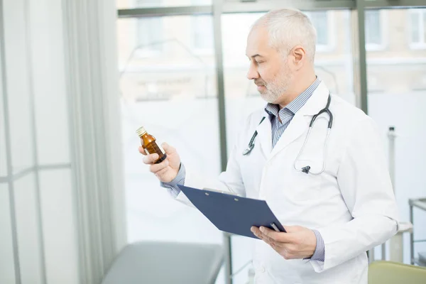 Médico Pelo Gris Mirando Medicina Botella Mano Mientras Trabaja Clínicas — Foto de Stock