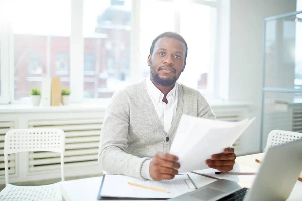 事務所の職場のそばに座って紙で自信を持って若いアフリカ系アメリカ人実業家 — ストック写真
