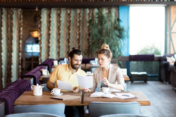 Dos Jóvenes Economistas Sentados Mesa Cafetería Moderna Mirando Través Papeles —  Fotos de Stock