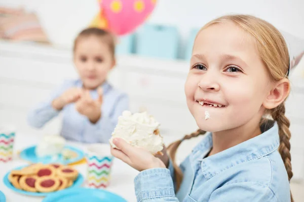 Menina Engraçada Comendo Bolo Aniversário Saboroso Enquanto Sentado Mesa Festiva — Fotografia de Stock