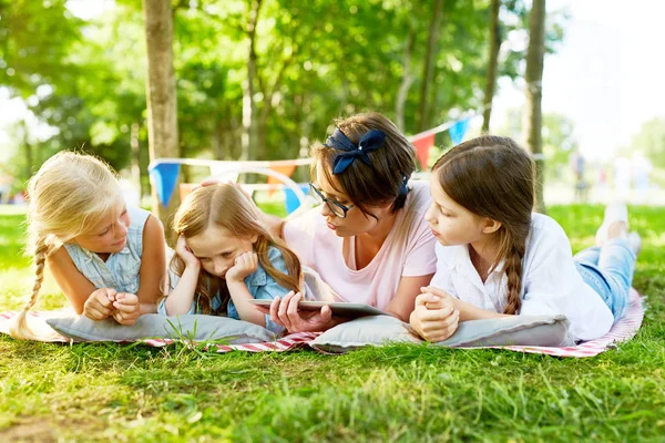 年轻的老师和两个朋友看反复无常的女孩 而在夏天放松户外 — 图库照片