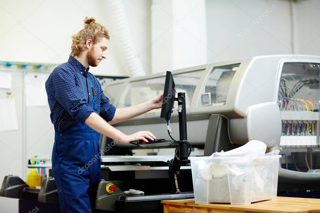 Typographer working with printing machine on factory