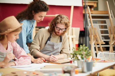 Bazı ilkeleri açıklarken iki kız onun not defterinde çizim kendi grup arkadaşı bakarak