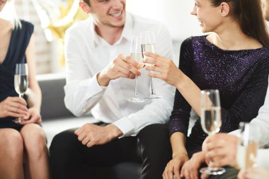 Genç ve gösterişli bir çift, arkadaşları arasında şampanya kadehleriyle parti veriyor.