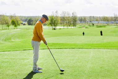 Yeşil alanın ortasında duran ve golf topu vurmak gitmek giyim kıdemli adam