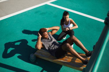 Zaman siyah adam sporcu yer, egzersiz bankta egzersizi yapıyor tutmak ciddi çekici genç hanım Koç