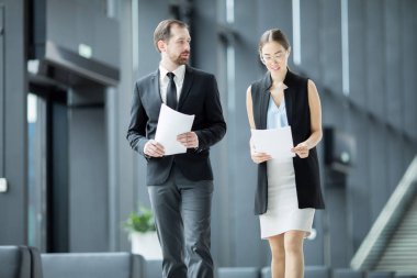 Genç iş kadını dinlenme odasında zarif bir ekonomistle yürürken gazete okuyor.