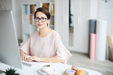 Genç ve güzel bir yönetici bilgisayar monitörü ve ağ kurulumu masasının önünde otururken sana bakıyor.