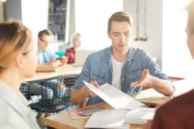 Modern ofiste toplantı sırasında başlangıç projesi üzerinde işbirliği yaparken fikir lerini tartışan yaratıcı iş profesyonelleri grubu, belge işaret yakışıklı genç adam odaklanmak , kopya alanı