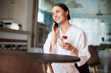 Spa kafede otururken, onun arkadaşı arıyorum ve içeceğinizi bornoz çağdaş esmer kız