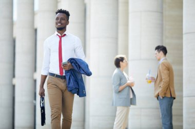 Şık iş kıyafeti mutlu amaçlı yakışıklı siyah adam işe gidiyor ve elinde ceket tutarak, o evrak çantası taşıyan