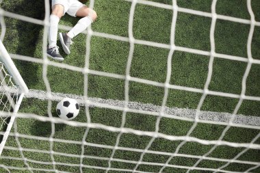Futbol topu net ve bacaklar yeşil sahada yalan kaleci gates içinde genel bakış