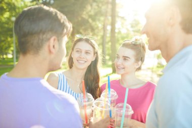 Parkta gezinti sırasında erkek arkadaşları ile konuşurken içecekler ile iki mutlu genç kadın