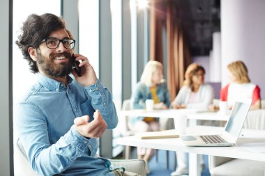 Ofiste otururken müşterilerden birini arayan akıllı telefon ile Gülümseyen ajan