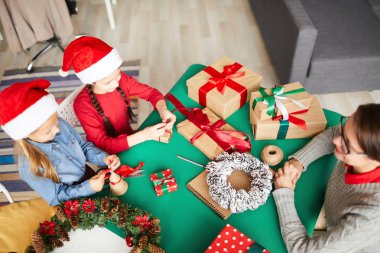 İki genç kız ve annelerinin masaya oturup xmas hediyeleri yapma ları