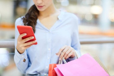 Smartphone ve yeni mesajları ve bildirimler alışveriş sonra kaydırma paperbags ile genç shopper