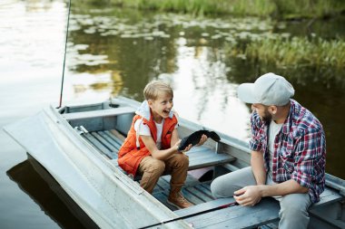 Neşeli çocuk o teknede otururken ve konuşurken yakalanan babası büyük balık gösteren