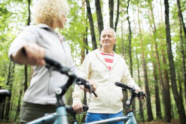 Bisikletiyle kıdemli adam ve eşi parkta yaz hafta sonu harcama