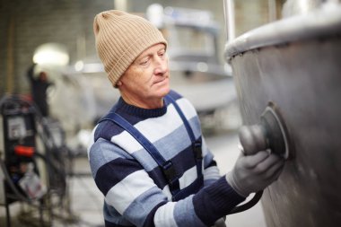 Cilalama makinesi ile yeni geminin metalik yüzeyini işleyen deneyimli gemi inşa mühendisi
