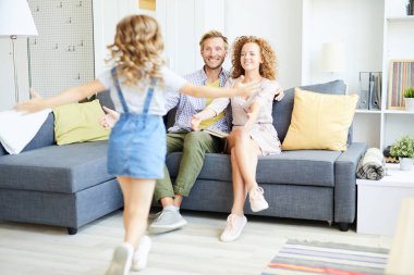 Genç mutlu çift kanepede oturuyor ve kollarını onlara doğru uzatıyor.