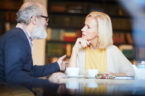 カフェで紅茶のカップでの会話中に髭の男を見ている金髪の女性 — ストック写真