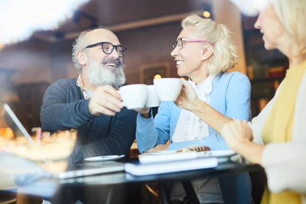 Feliz Seniors Tintineo Por Tazas Sobre Mesa Mientras Divierten Cafetería —  Fotos de Stock