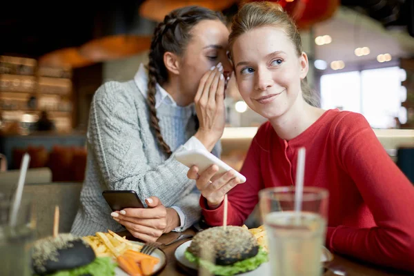 Dos Chicas Amigables Casuales Con Teléfonos Inteligentes Chismes Por Mesa — Foto de Stock