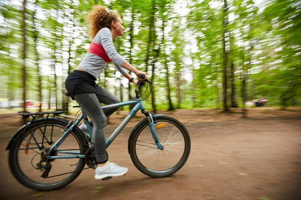 Young Sportswoman Riding Bicycle Road Forest Blurry Trees Both Sides — 스톡 사진