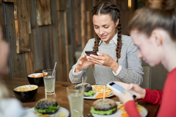 Zwei Freundliche Mädchen Die Smartphones Scrollen Während Sie Tisch Mit — Stockfoto