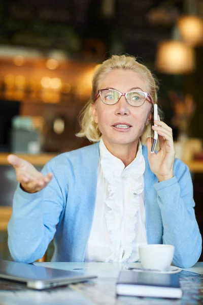 Ocupada Mulher Idosa Explicando Algo Smartphone Enquanto Sentada Mesa Organizando — Fotografia de Stock