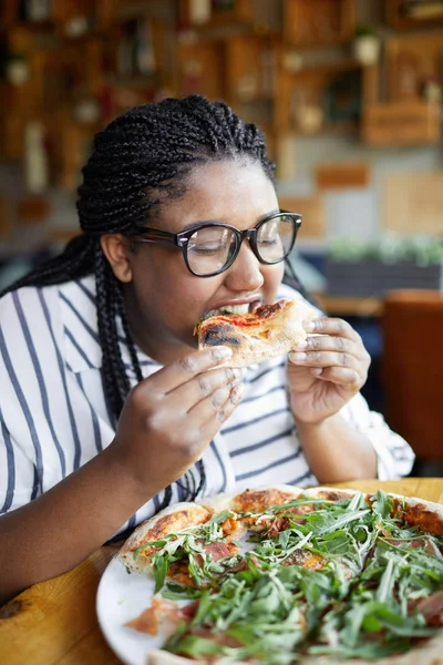 饥饿的女人咬美味的比萨饼在盘子上与几个片更多的午餐 — 图库照片