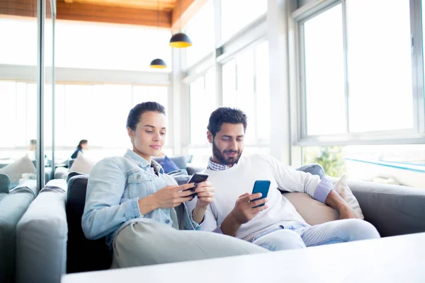 Joven Pareja Moderna Ropa Casual Relajante Cafetería Búsqueda Sus Teléfonos — Foto de Stock