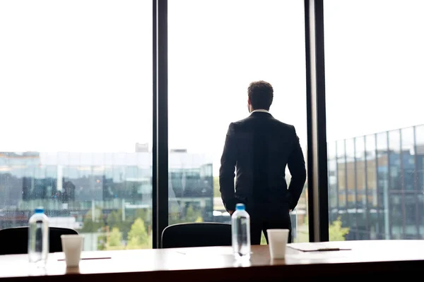 Kontemplacyjny Biznesmen Formalnym Garniturze Trzymający Rękę Kieszeniach Patrząc Panoramiczne Okno — Zdjęcie stockowe