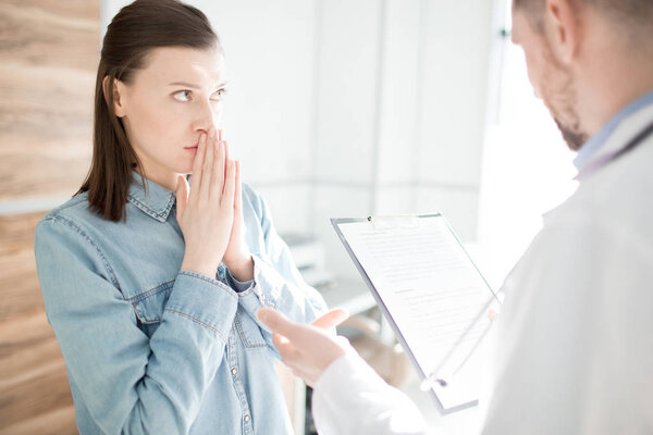 Anxious patient listening to doctor advice and prescription notice during appointment