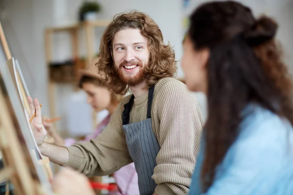 Jovem Feliz Consultando Seu Colega Grupo Lição Pintura Enquanto Sentado — Fotografia de Stock