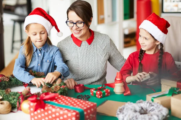 幸せな若い女性と小さな女の子はクリスマスリースを作り コーンでそれを飾る — ストック写真