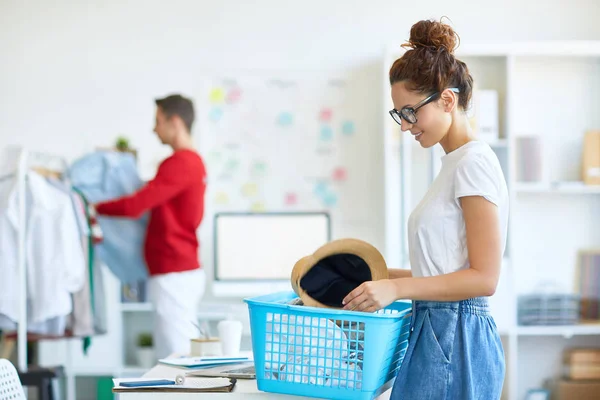 Junge Frau Freizeitkleidung Holt Hut Aus Plastikbox Mit Verschiedenen Sachen — Stockfoto