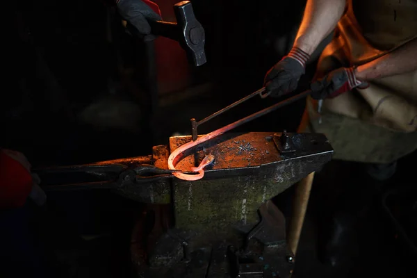 一起生产金属部件的无法辨认的铁匠的特写镜头 其中一人拿着加热棒和火铁 而他的同事则用手工具敲击细节 — 图库照片