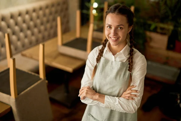 Ευτυχισμένη Νεαρή Σερβιτόρα Ρούχα Εργασίας Κοιτάζοντας Σας Χαμόγελο Άδειο Καφέ — Φωτογραφία Αρχείου
