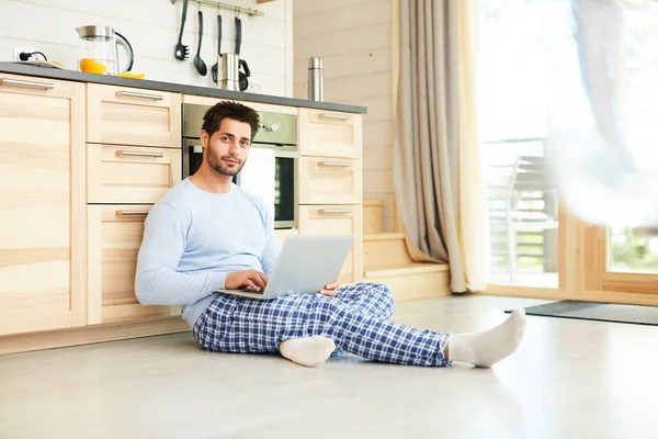 Zufriedene Junge Bärtige Freiberufler Sitzen Auf Dem Boden Und Schauen — Stockfoto