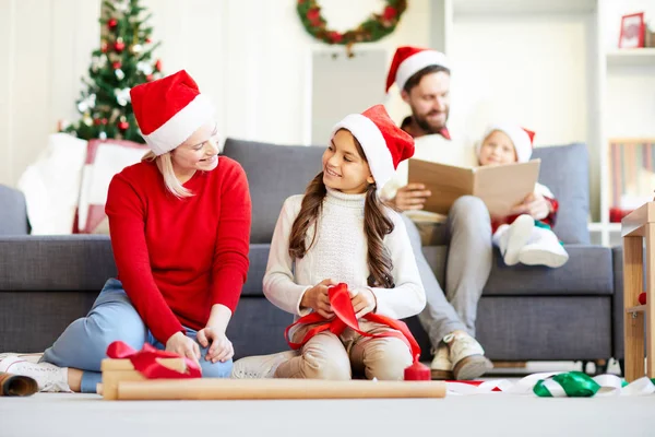 Jovem Feliz Uma Suas Filhas Bonés Papai Noel Sentado Chão — Fotografia de Stock