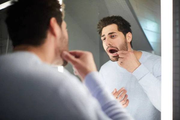 英俊的年轻人 保持嘴张开 而检查牙齿和看镜子在浴室 — 图库照片